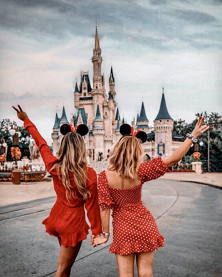 Two girls stand in front of Cinderella's castle at Walt Disney World holding hands